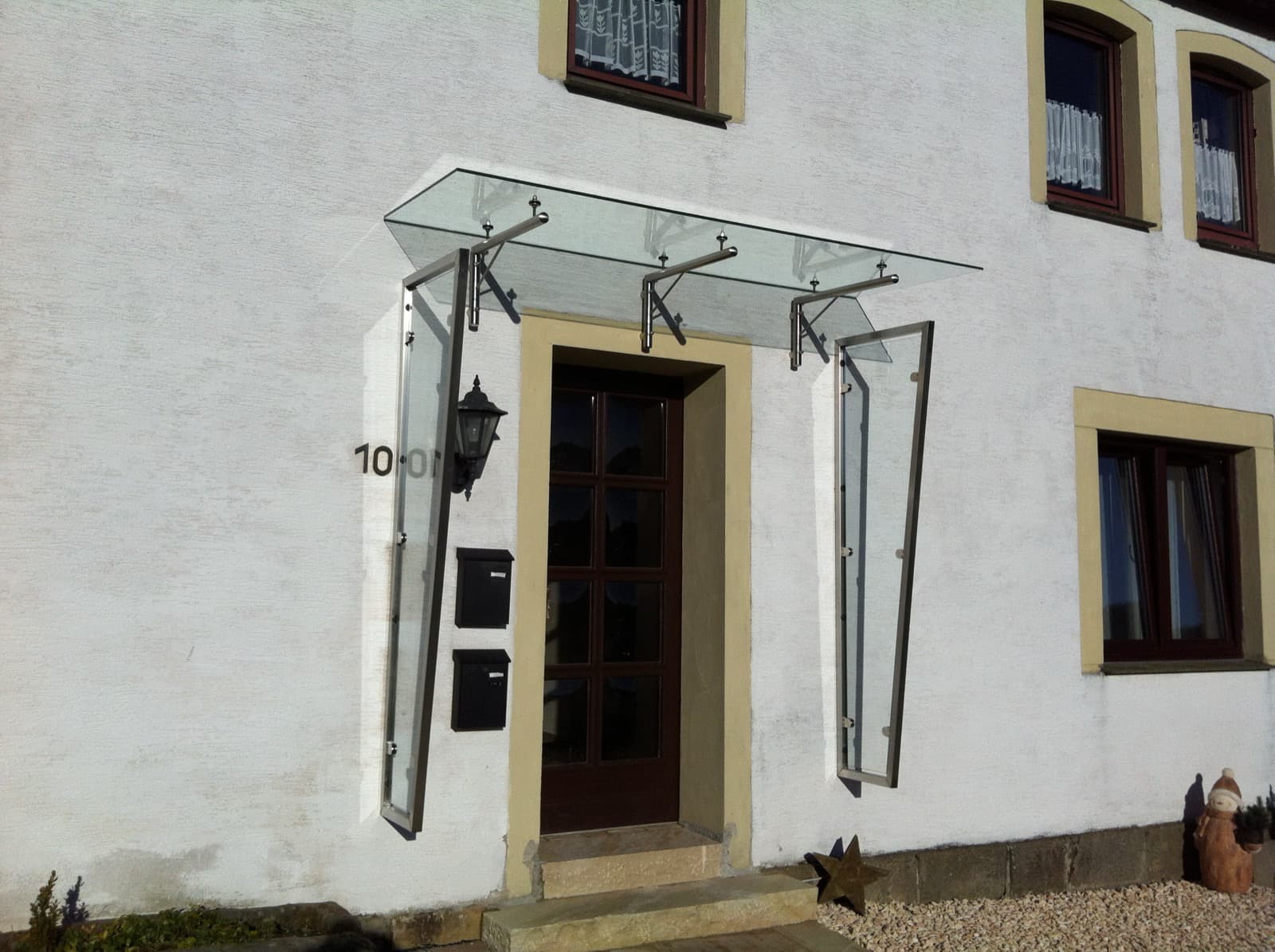 Modernes Vordach aus Edelstahl und Glas an einer Haustür